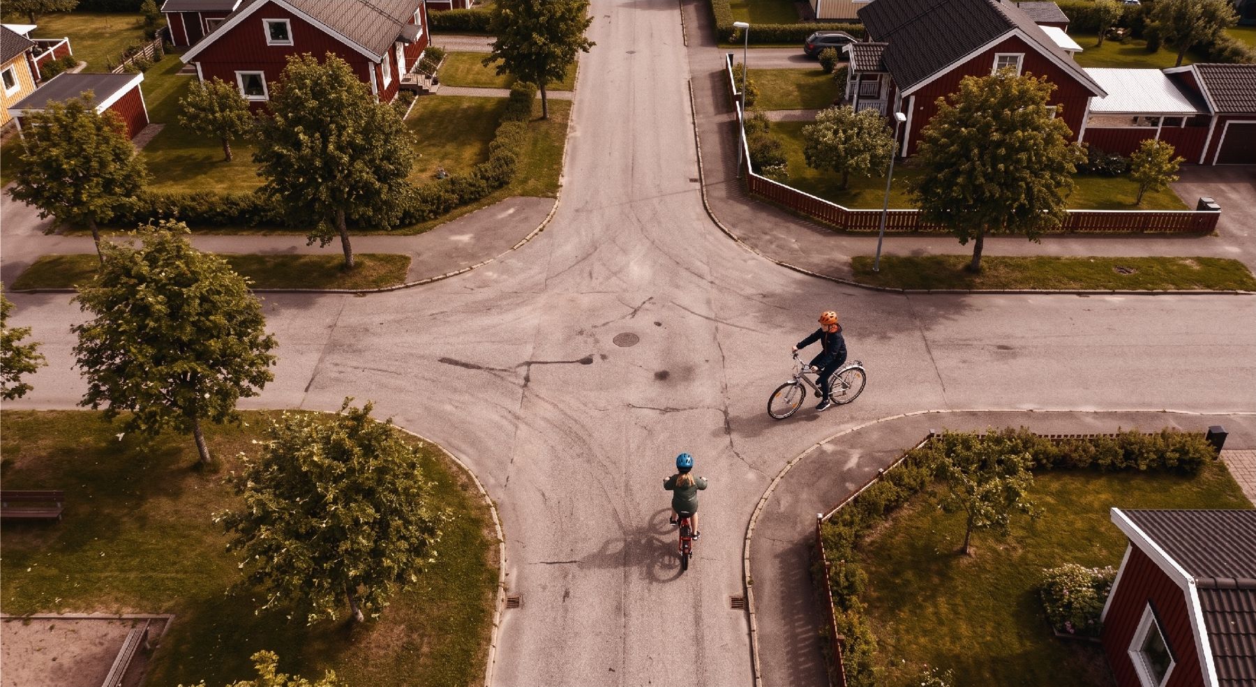 Flygbild över en korsning i ett villaområde med två cyklister